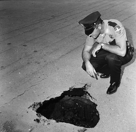 Police Officer looking at pothole in roadway